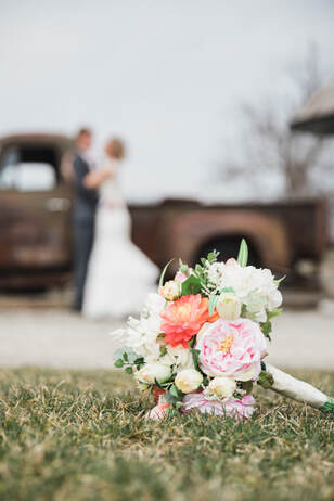 wedding bouquet on the ground with blurred couple in the background